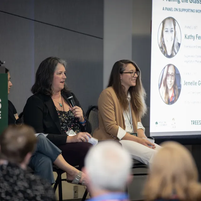 Two people speaking on a panel at conference